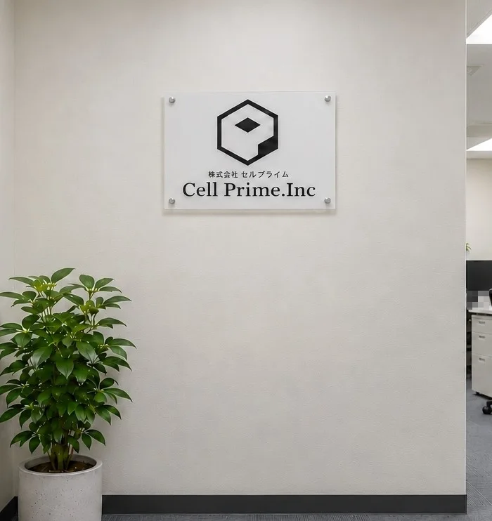 セルプライムの受付。白い壁に「株式会社セルプライム Cell Prime.Inc」のサインがかかり、手前に観葉植物が置かれている
