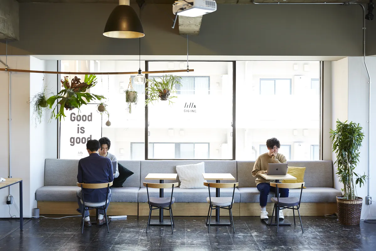 GIGのオフィスのソファ席。窓に「Good is good.」の文字があり、メンバーがくつろいで話したり作業したりしている