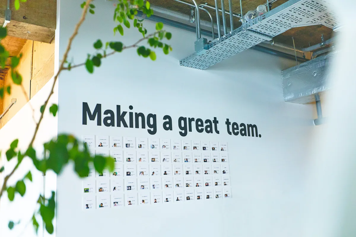 GIGのオフィスの白い壁。バリューのひとつ「Making a great team.」の文字の下に、メンバーの顔写真のカードが並んでいる