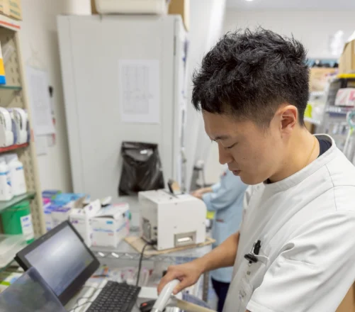白衣の薬剤師が、調剤室のパソコンに向かって入力している